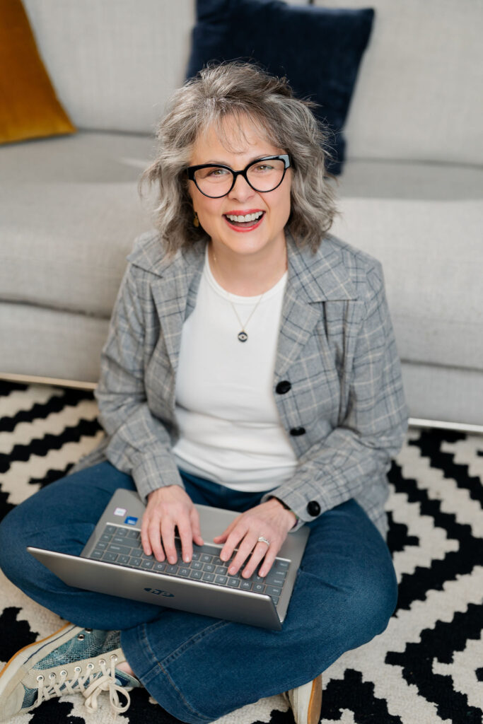 Rebecca Pixley seated with crossed legs working on digital marketing on a laptop